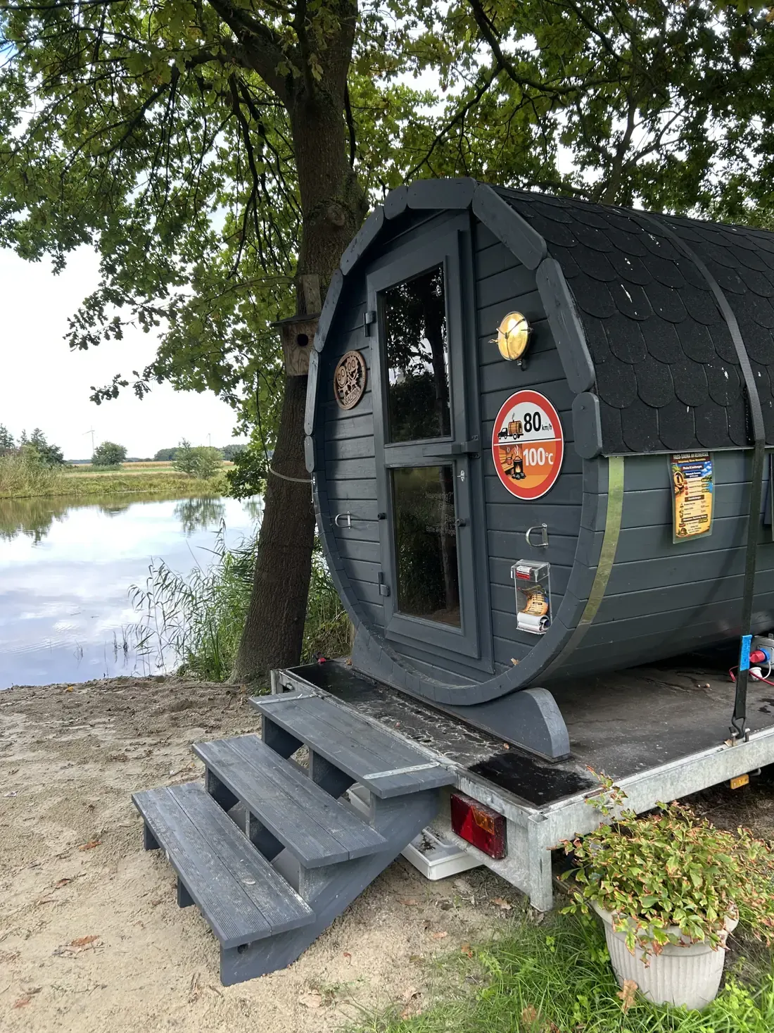 Fasssauna mit Treppe und Glastür am Ufer des Reihersees