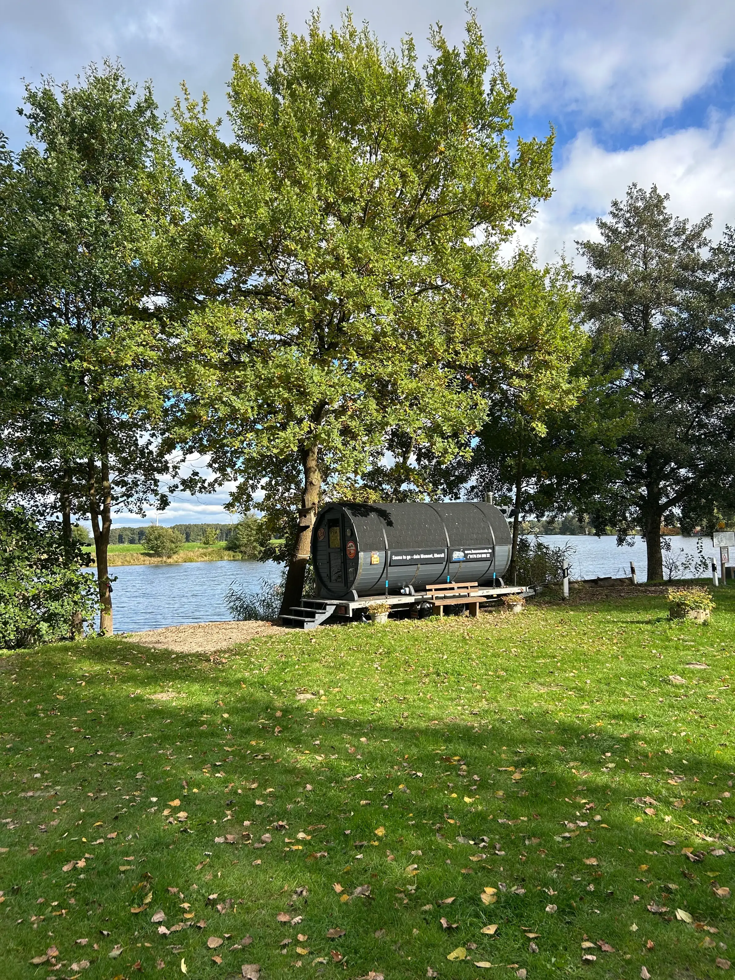 Fasssauna unter einer Eiche auf der Wiese am Ufer des Reihersees bei Brietlingen