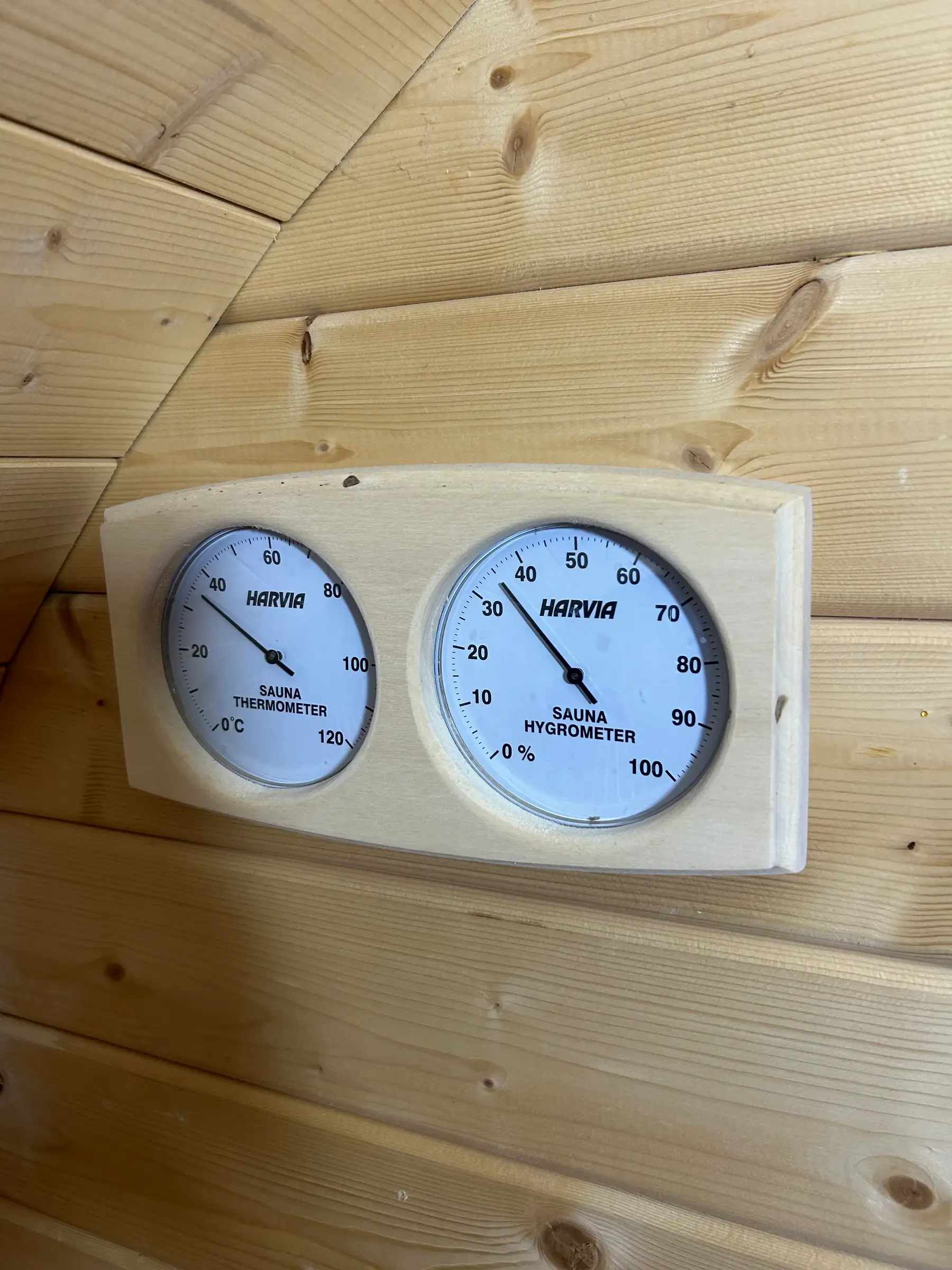 Thermometer und Hygrometer von Harvia an der Holzwand der Fasssauna
