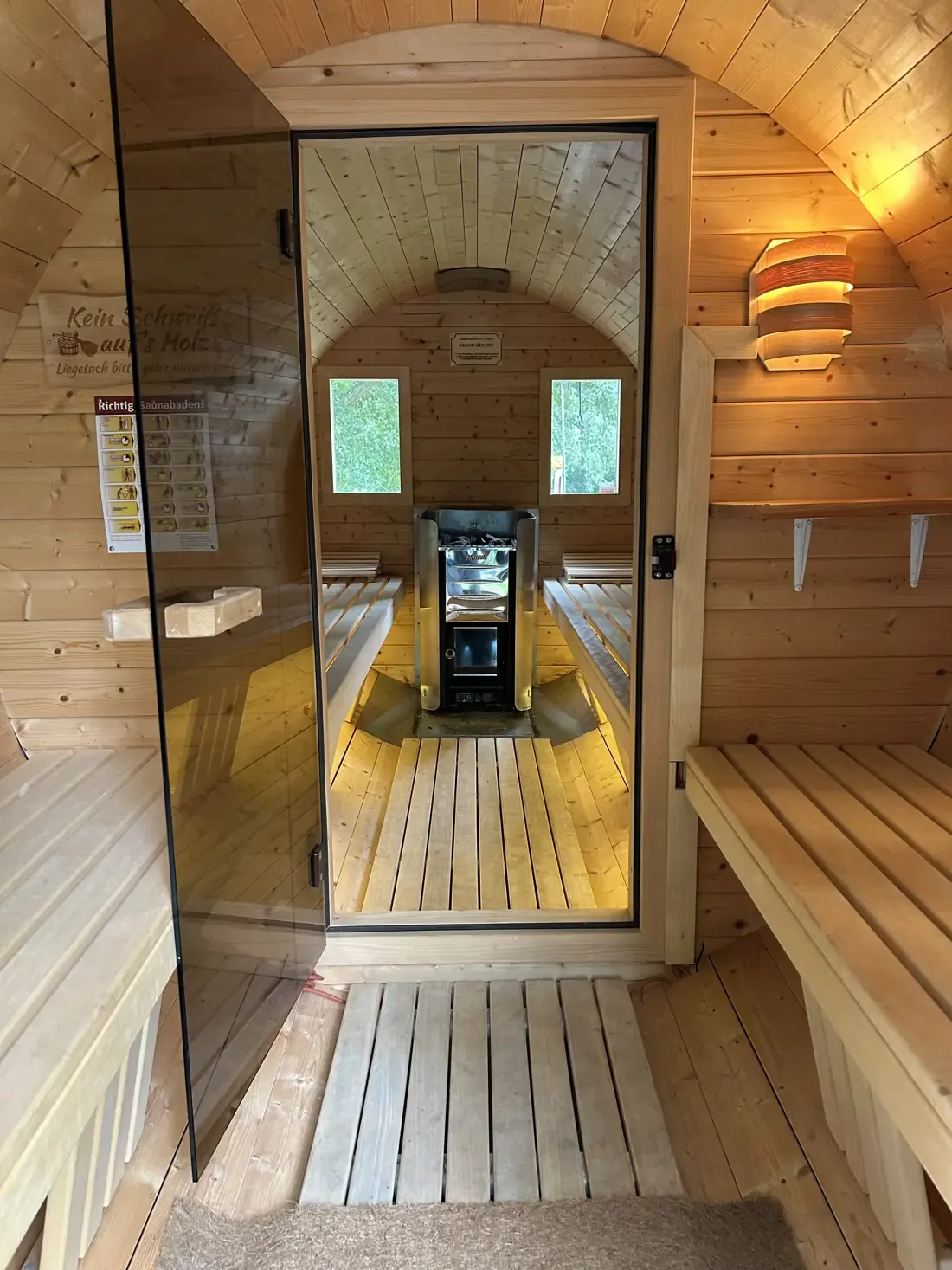 Vorraum der Fasssauna mit Sitzbank und Blick in den Saunaraum