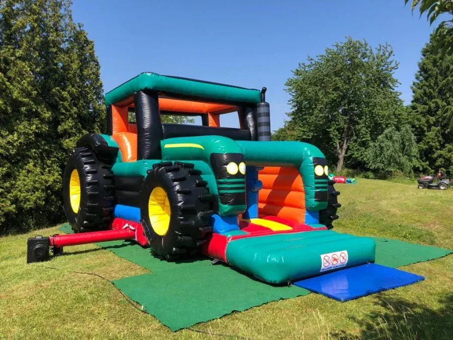 XXL-Hüpfburg Traktor in Grün mit großen Reifen auf einer Wiese